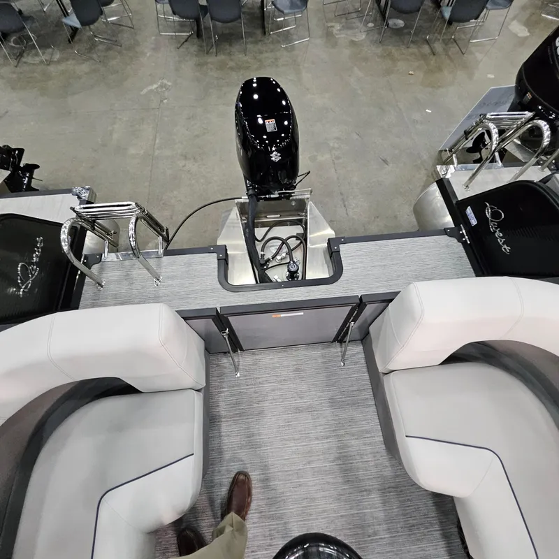 Slide: The Image of 2025 Qwest E 20RLS boat interior with seating and motor, displayed indoors. - 23