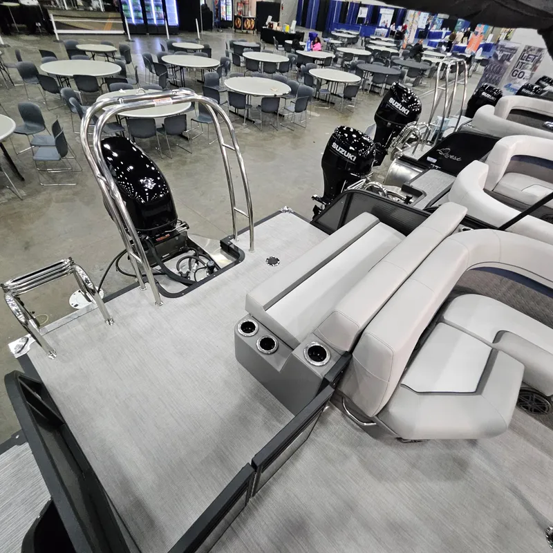 Slide: The Image of 2025 Qwest L22 Lanai pontoon boat interior with seating and outboard motors in showroom. - 15