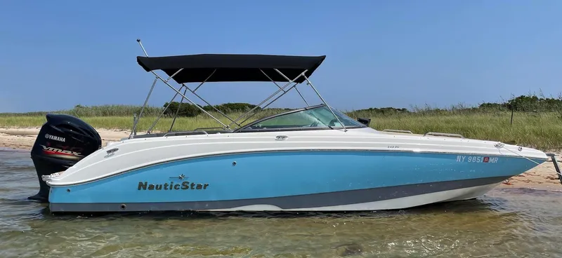Slide: The Image of 2021 NauticStar 243 DC boat with Yamaha engine, anchored on a sandy beach. - 0