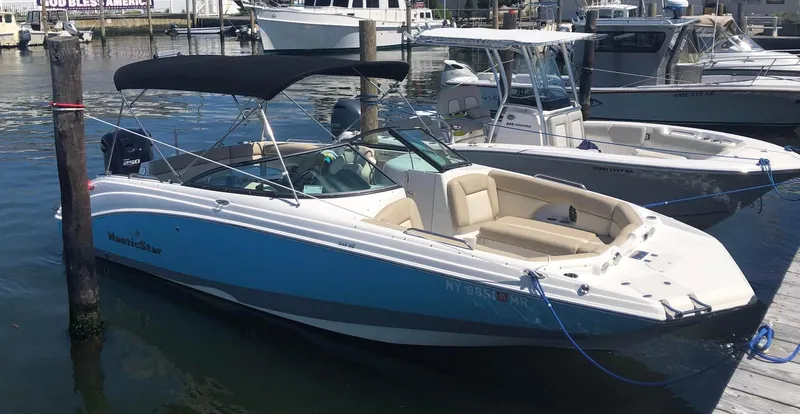 Slide: The Image of 2021 NauticStar 243 DC boat docked in marina, featuring sleek design and spacious seating. - 5