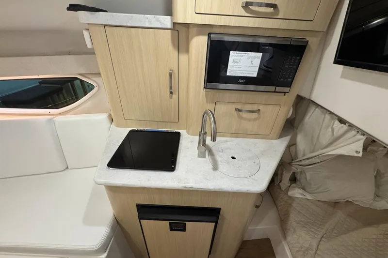 Slide: The Image of 2025 Regal 28 Express boat interior with kitchenette, featuring microwave, sink, and storage cabinets. - 15