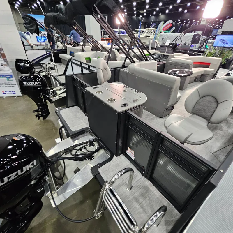 Slide: The Image of 2025 Qwest E 20XRE pontoon boat interior at a boat show, featuring Suzuki engines. - 12