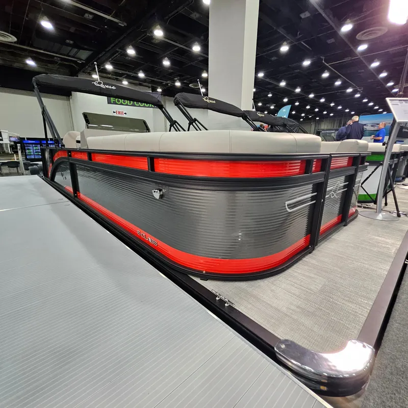 Slide: The Image of 2025 Qwest E 20XRE pontoon boat displayed indoors with modern design and vibrant red accents. - 16