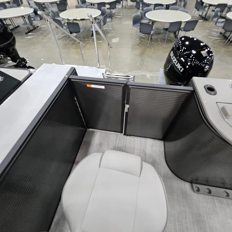 Slide: The Image of 2025 Qwest E 20XRE boat interior with seating and Suzuki engine in showroom. - 26
