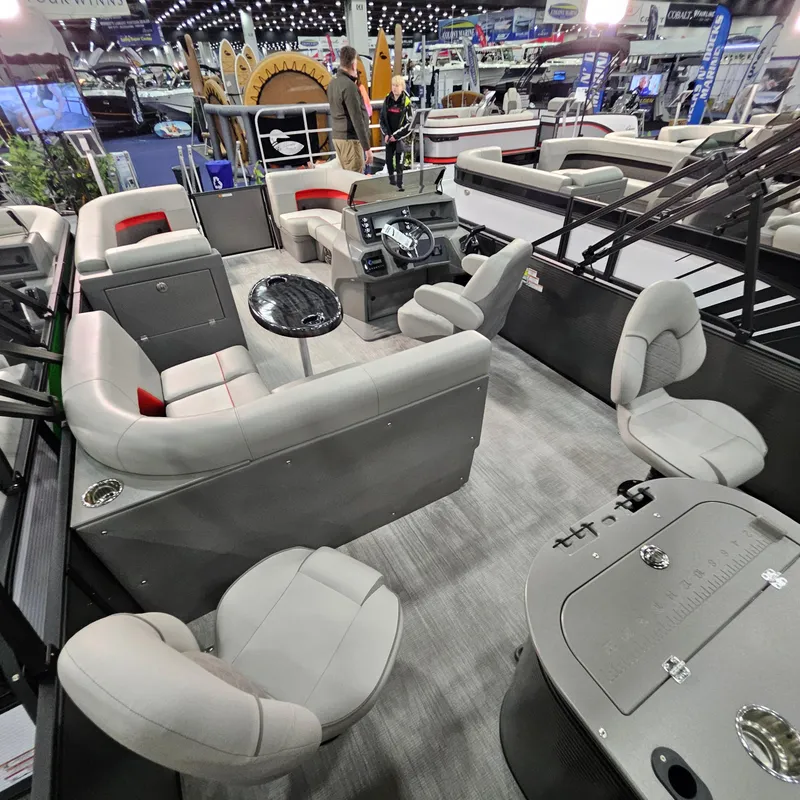 Slide: The Image of 2025 Qwest E 20XRE pontoon boat interior with plush seating and modern dashboard at a boat show. - 28