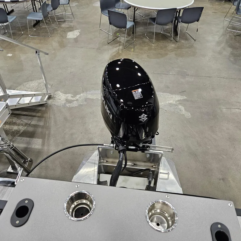 Slide: The Image of 2025 Qwest E 20XRE boat motor displayed indoors, surrounded by chairs and tables. - 9