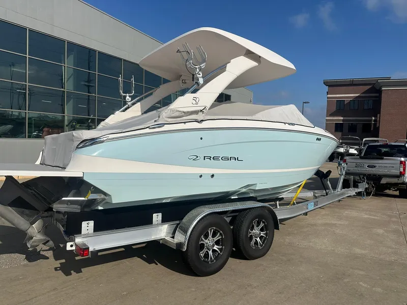 Slide: The Image of 2022 Regal LS4 Surf boat on trailer, parked outside a building. - 1