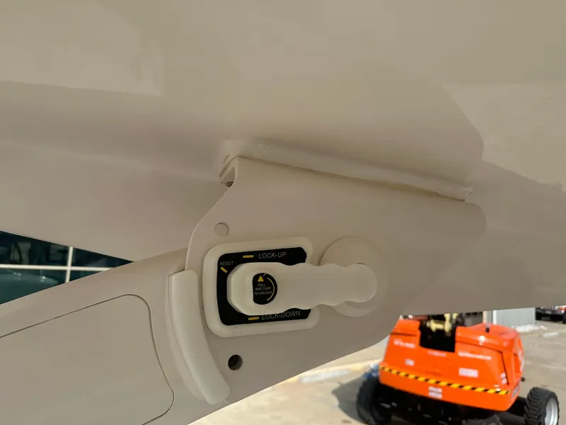 Slide: The Image of 2022 Regal LS4 Surf boat canopy lock mechanism with outdoor equipment in background. - 19