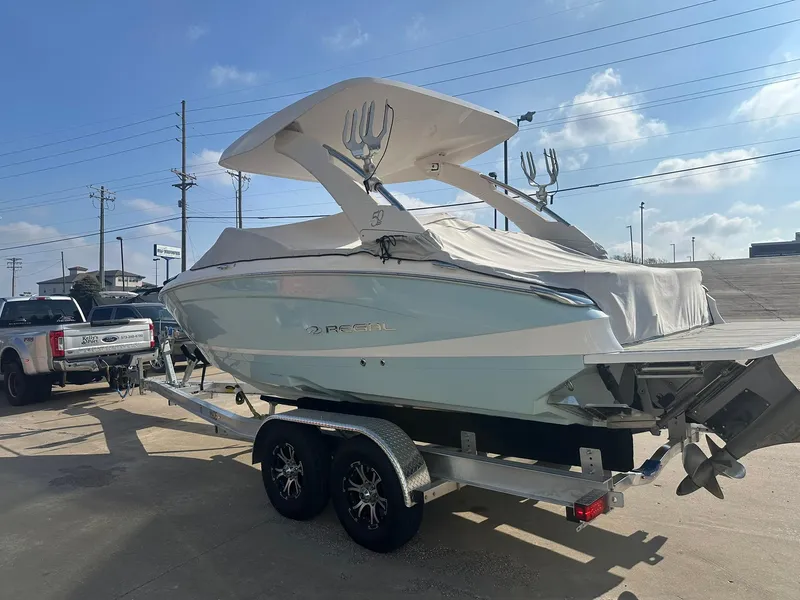 Slide: The Image of 2022 Regal LS4 Surf boat on trailer under clear sky. - 2