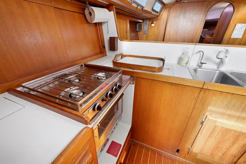 Slide: The Image of 1986 J Boats J/40 yacht kitchen with stove, sink, and wooden cabinetry. - 43