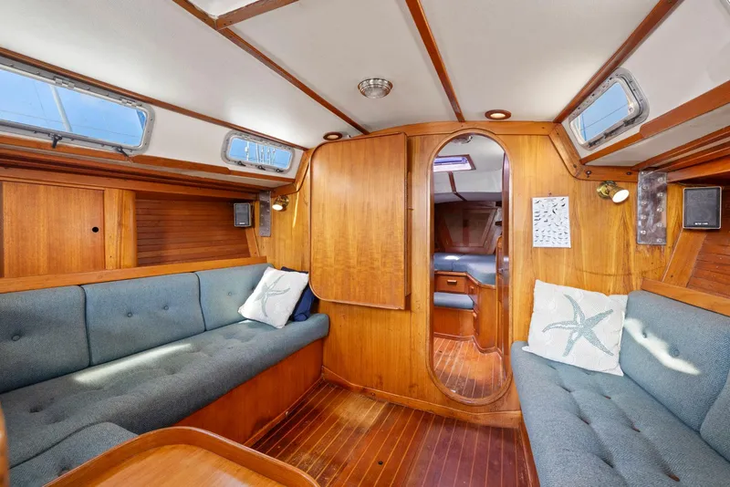 Slide: The Image of 1986 J Boats J/40 interior with wooden finish, blue seating, and nautical decor. - 47