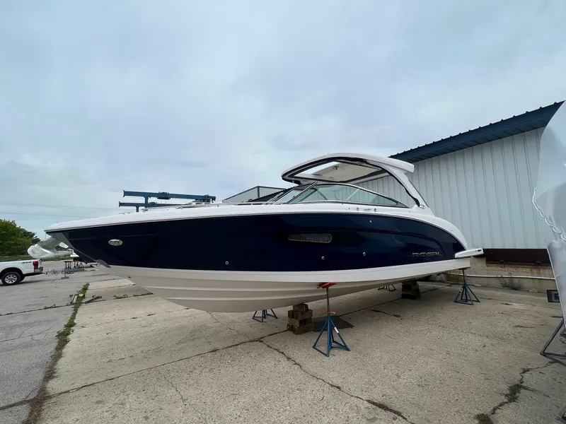 The Image of 2025 Regal 3300 boat on stands, blue and white design, dockside view. - 0