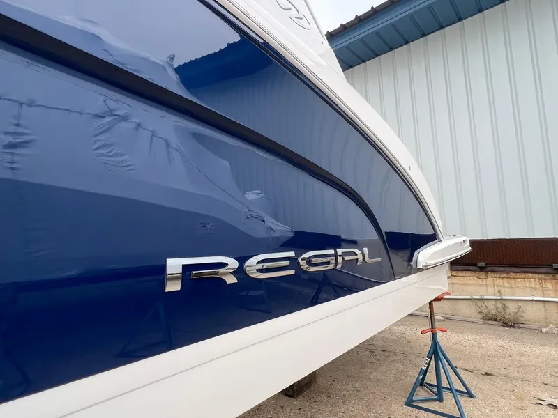 Slide: The Image of 2025 Regal 3300 boat side view with blue and white exterior in storage. - 4