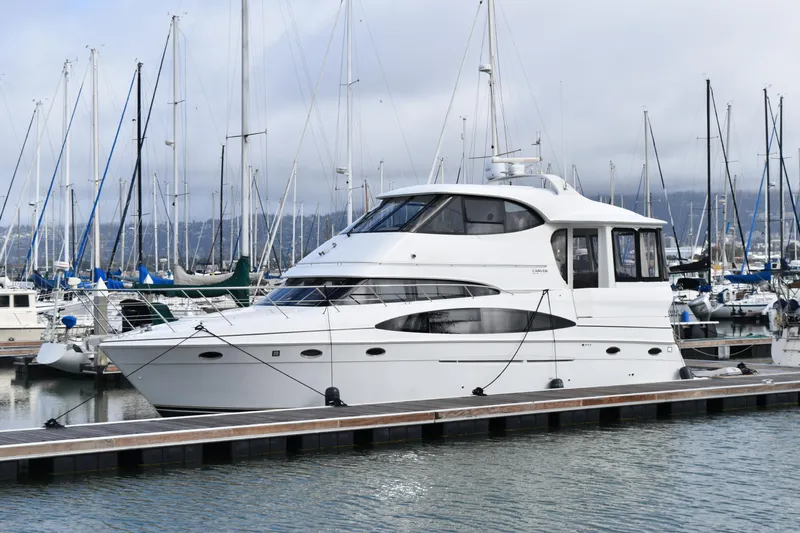 Slide: The Image of 2000 Carver 506 Motor Yacht docked in a marina with sailboats in the background. - 0