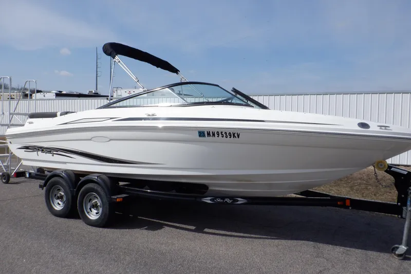 Slide: The Image of 2012 Sea Ray 205 Sport boat on trailer, white exterior, parked outdoors. - 1