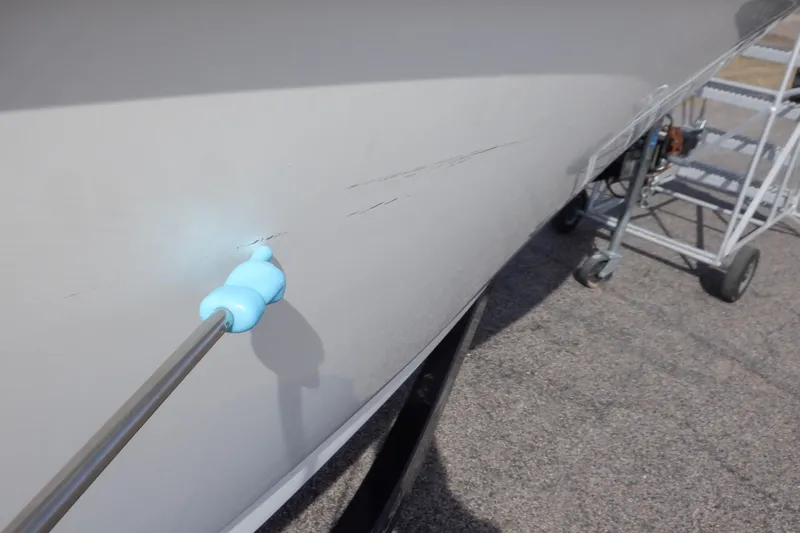 Slide: The Image of 2012 Sea Ray 205 Sport boat hull with visible scratches and repair tool. - 45