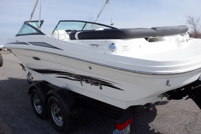 Slide: The Image of 2012 Sea Ray 205 Sport boat on trailer, white with black accents, parked outdoors. - 6