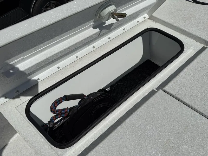 Slide: The Image of Open storage compartment on a 2022 Avid 19 FS boat, containing a coiled rope. - 11