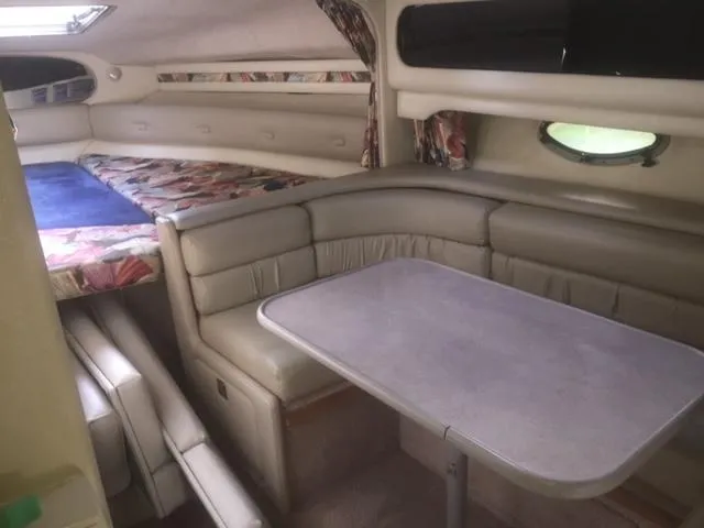 Slide: The Image of 1997 Chaparral 31 boat interior with dining area and bed, featuring beige seating and floral accents. - 6
