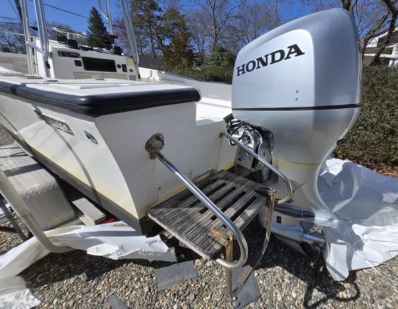 Slide: The Image of 1994 Mako 231 boat with Honda outboard motor, docked on gravel. - 19