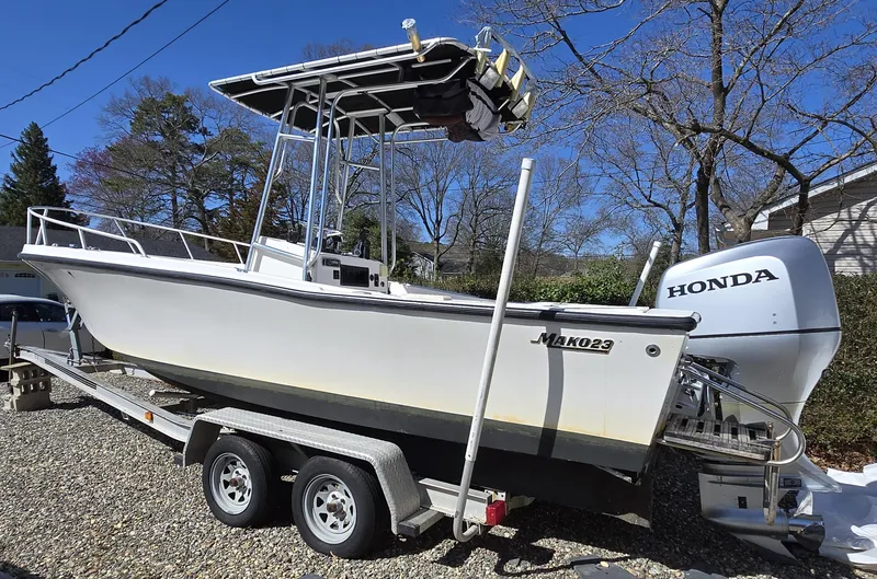 Slide: The Image of 1994 Mako 231 boat on trailer with Honda outboard motor, parked outdoors. - 21