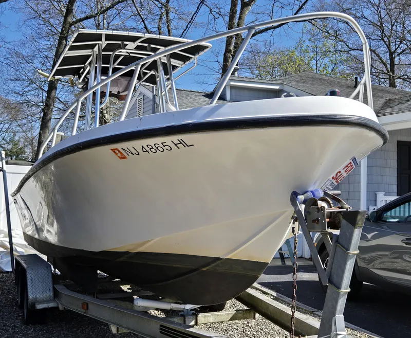 Slide: The Image of 1994 Mako 231 boat on trailer, parked outdoors near trees and a house. - 22