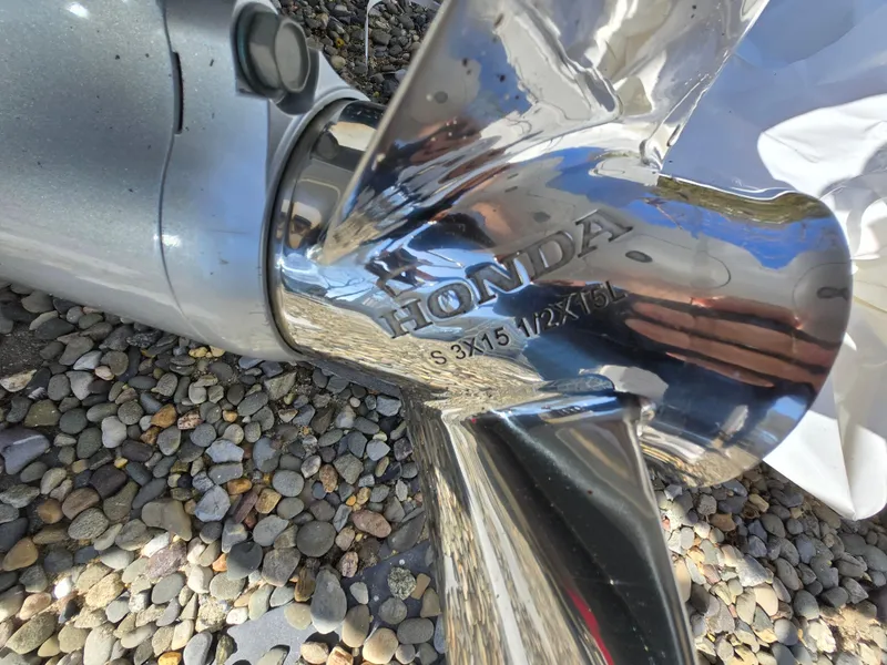 Slide: The Image of Close-up of a Honda boat propeller on a 1994 Mako 231, resting on pebbles. - 24