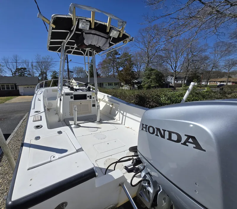 Slide: The Image of 1994 Mako 231 boat with Honda outboard motor, parked outdoors under clear blue sky. - 25