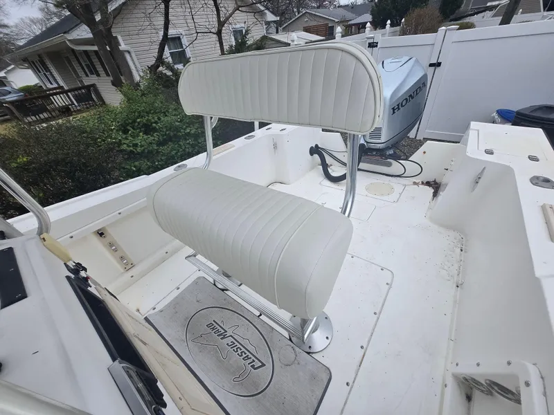 Slide: The Image of 1994 Mako 231 boat interior with white cushioned seating and Honda outboard motor. - 29