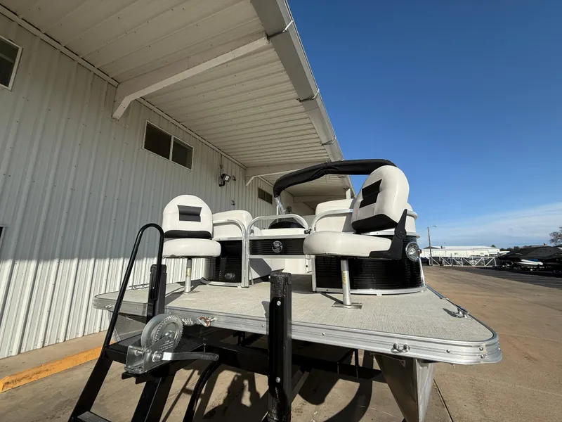 Slide: The Image of 2018 Landau Island Breeze 212C pontoon boat with white seating, parked under a metal roof. - 14