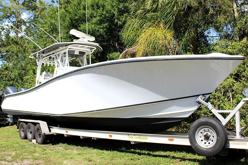 Slide: The Image of 2007 Yellowfin 36 Offshore boat on trailer, surrounded by lush greenery. - 1