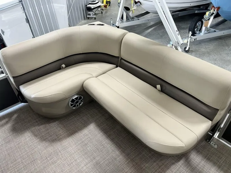 Slide: The Image of 2025 Sun Tracker PARTY BARGE® 16 DLX beige seating with speaker, in showroom setting. - 11