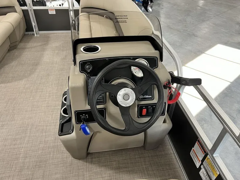 Slide: The Image of 2025 Sun Tracker PARTY BARGE® 16 DLX steering console with beige seating and modern controls. - 12