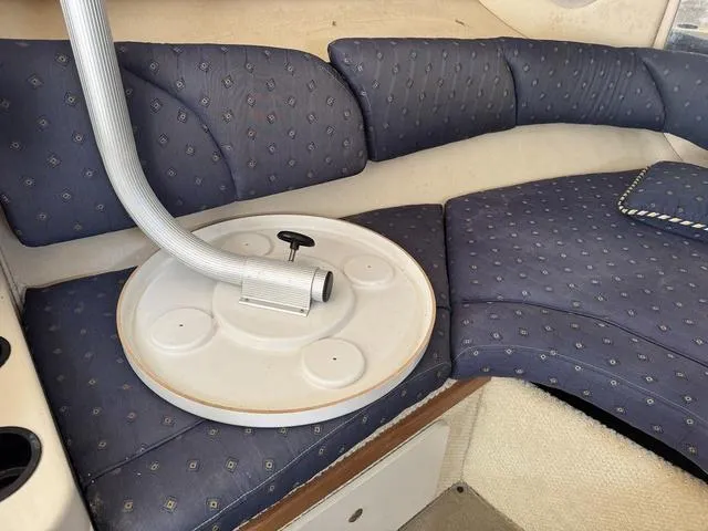 Slide: The Image of Interior seating of 2002 Sea Ray 260 Sundancer boat with blue cushions and table. - 16