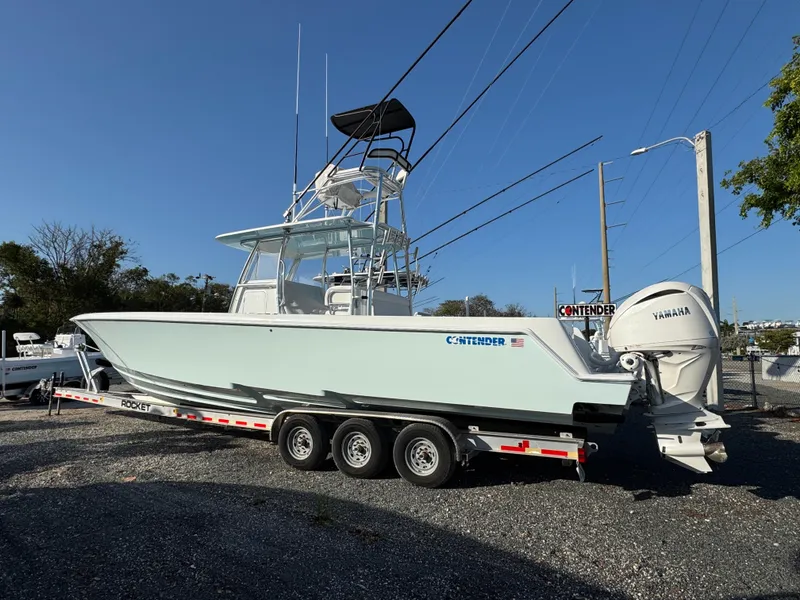 Slide: The Image of 2024 Contender 39 ST boat on trailer with Yamaha engines, parked outdoors. - 2