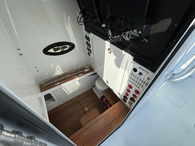 Slide: The Image of 2024 Contender 39 ST boat interior with control panel, wooden flooring, and compact restroom. - 29