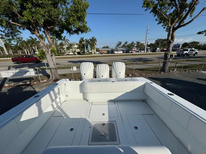 Slide: The Image of 2024 Contender 39 ST boat with triple engines, docked near a road and trees. - 30