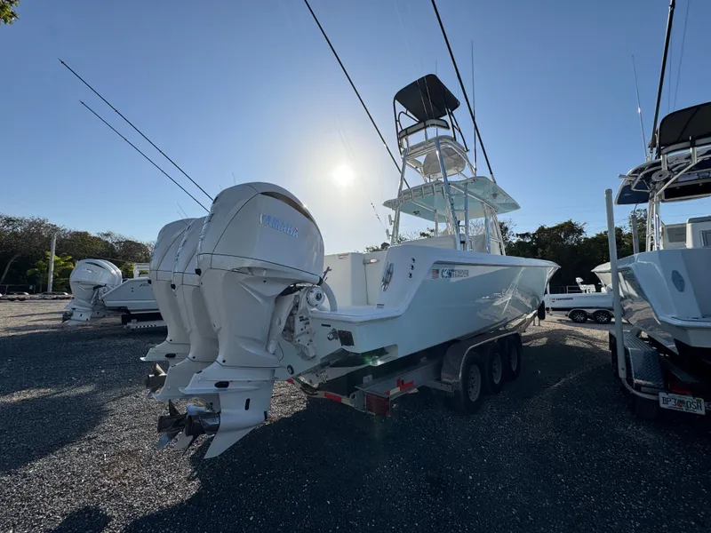 Slide: The Image of 2024 Contender 39 ST boat with triple outboard engines on a trailer, parked outdoors. - 7