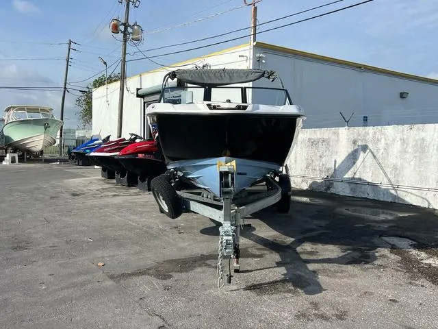 Slide: The Image of 2024 Yamaha Boats SX220 on trailer, parked outdoors near other watercraft. - 2