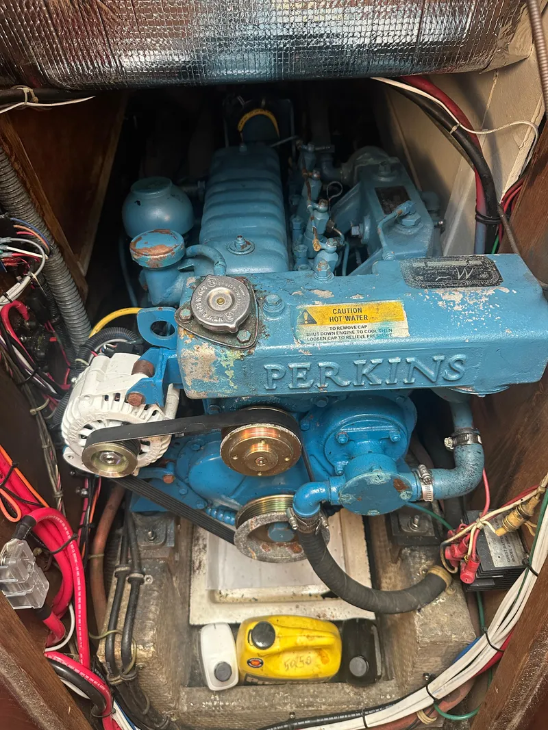 Slide: The Image of 1980 Morgan 382 sailboat engine, Perkins brand, blue color, surrounded by wiring and components. - 15