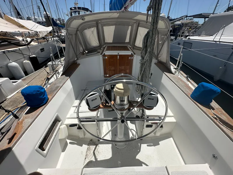 Slide: The Image of 1980 Morgan 382 sailboat cockpit with steering wheel, docked at marina. - 2