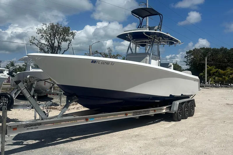 Slide: The Image of 2023 Contender 32 ST boat on trailer, parked outdoors under a cloudy sky. - 15