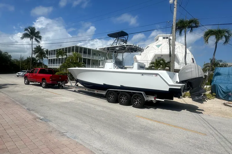 Slide: The Image of Red truck towing 2023 Contender 32 ST boat on a sunny street with palm trees. - 17