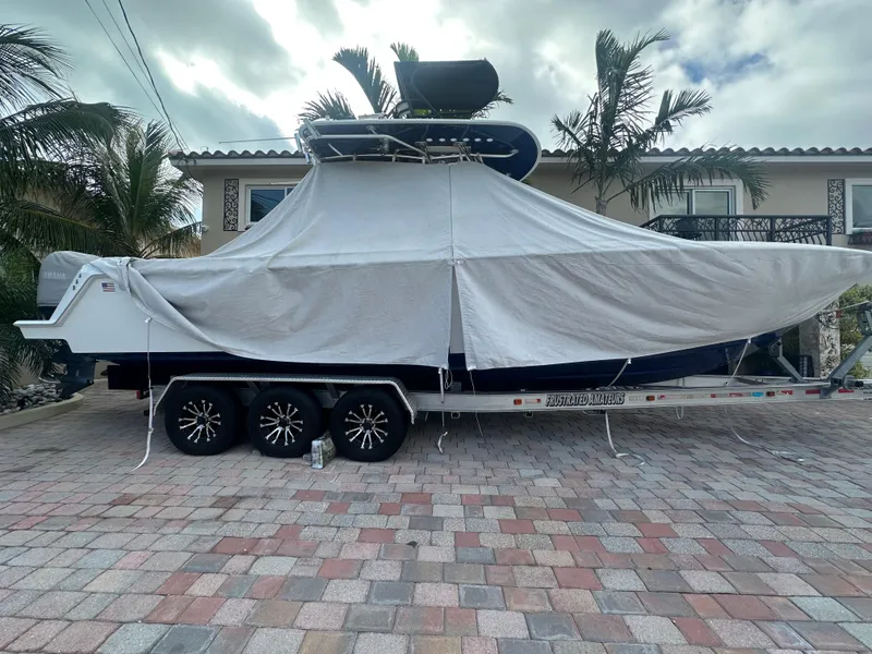 Slide: The Image of 2023 Contender 32 ST boat covered on a trailer, parked in a driveway. - 18