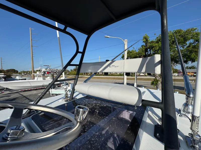 Slide: The Image of 2023 Contender 32 ST boat helm with steering wheel and controls, outdoor setting. - 28
