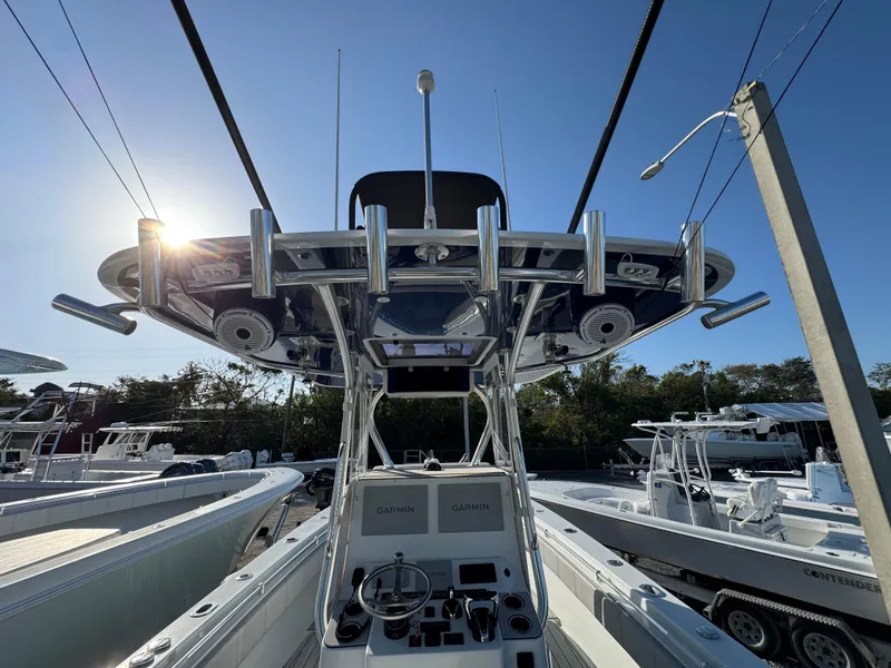 Slide: The Image of 2023 Contender 32 ST boat, center console view, rod holders, clear sky, marina setting. - 43