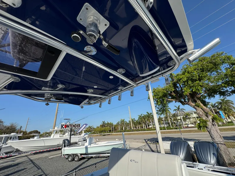 Slide: The Image of 2023 Contender 32 ST boat with blue canopy and dual engines, parked outdoors. - 45