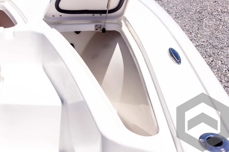 Slide: The Image of 2025 Tidewater 2110 Bay Max boat storage compartment, open lid, white interior, gravel background. - 28