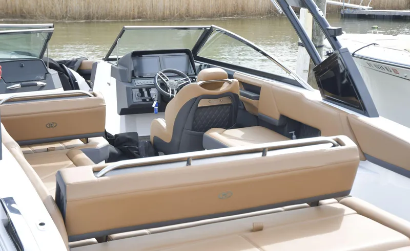 Slide: The Image of 2022 Cobalt R6 boat interior with tan seating and modern dashboard on a calm waterway. - 10