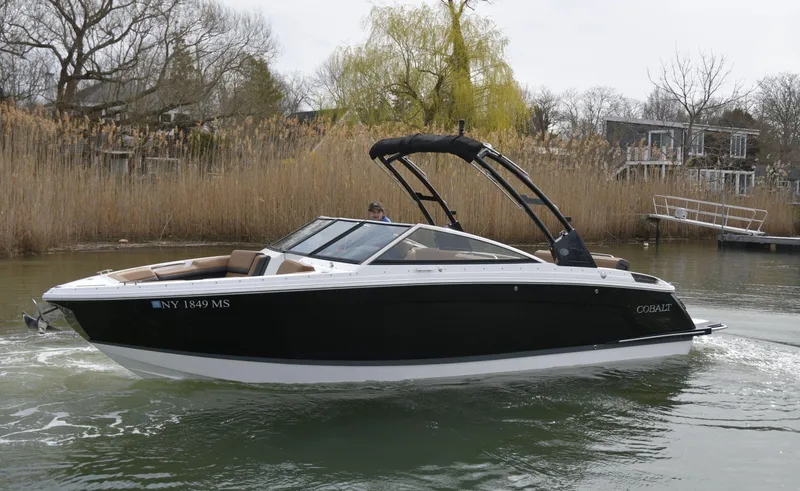 Slide: The Image of 2022 Cobalt R6 boat cruising on a calm river with reeds in the background. - 2